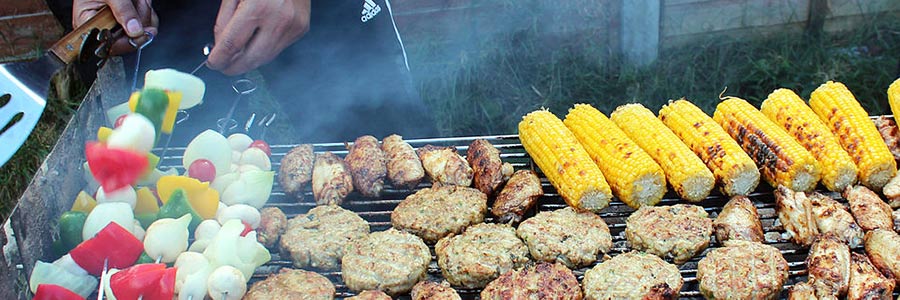 Vegetable skewers, corn on the cob, and meats on a barbeque