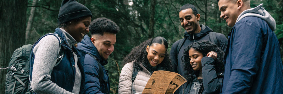 youngsters happily looking at a map in the middle of a forest